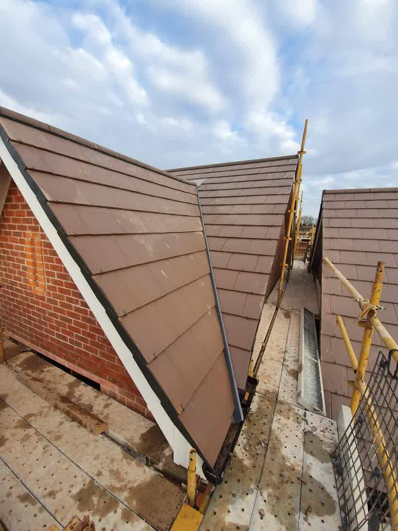 Brown tiles run up to a brick gable with the scaffold still in place