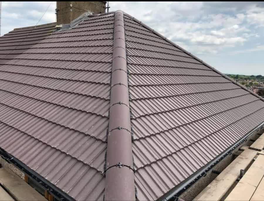 Finished tiled roof with a clean hip and a bedded ridge under an open sky
