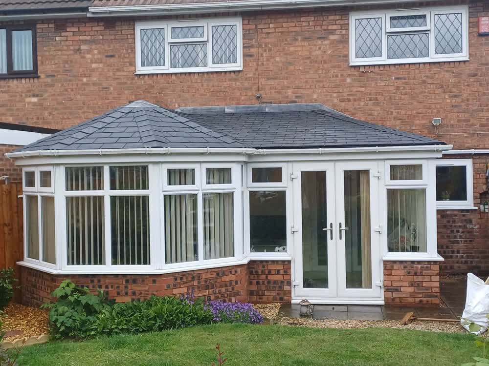 Bungalow with a bay conservatory under a new dark tiled roof