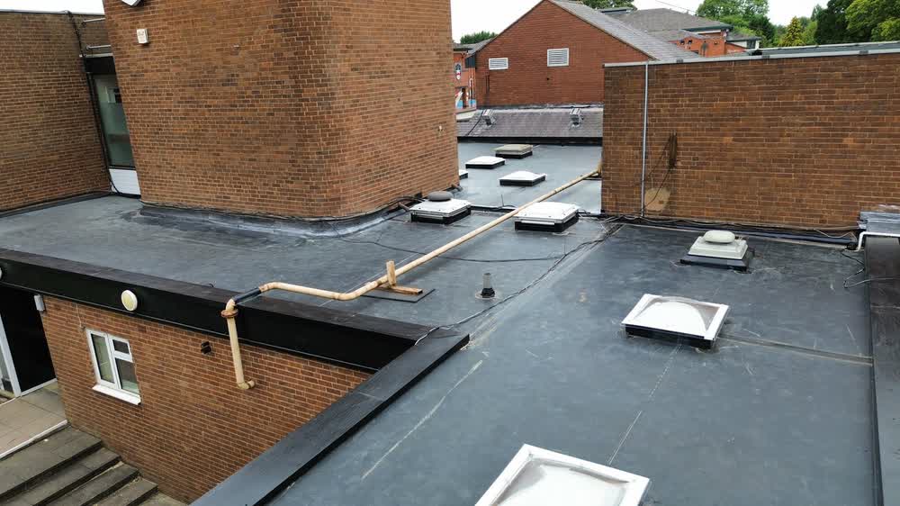 Large commercial flat roof with dome rooflights and brick parapets